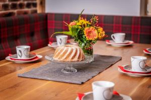 una mesa con un pastel y un jarrón de flores en Alpen Chalet Wohnung "Martha" en Zellberg