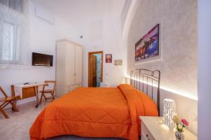 1 dormitorio con cama de color naranja y escritorio en Casa Hermes, en Atrani
