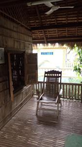 una mecedora sentada en un porche de madera en OBT - The Coconut Bungalow 