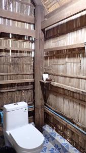 baño con aseo y paredes de madera en OBT - The Coconut Bungalow 