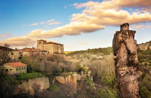 una estatua de un hombre en una colina con un castillo en el fondo en El Mirador de Almanzor, en Calatañazor