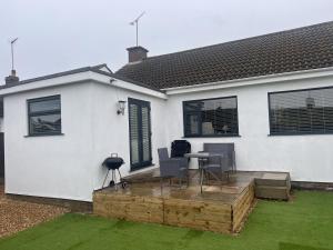 a white house with a table and chairs on a deck at Inviting 2-Bed Bungalow in Heacham with spa bath in Heacham