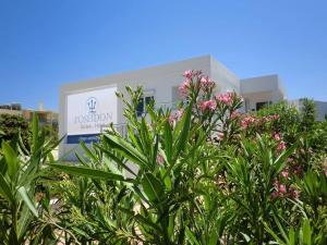 una planta con flores rosas frente a un edificio en Poseidon Suites Hotel en Stavros