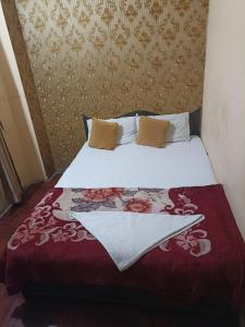 een slaapkamer met een bed met een rode en witte deken bij Hotel Opera in Bharatpur