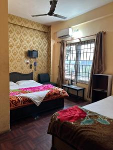 a hotel room with two beds and a window at Hotel Opera in Bharatpur