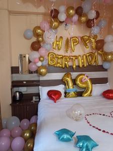 a bed with balloons and a sign that says happy birthday at Hotel Opera in Bharatpur