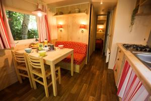 una pequeña cocina con mesa y sofá en Camping Les Cruses, en Ribes