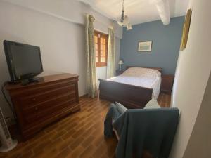 una camera con letto, TV e sedia di La Maison Vieille a Peillon