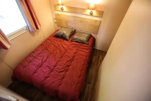 een kleine slaapkamer met een rood bed en een raam bij Camping Les Cruses in Ribes
