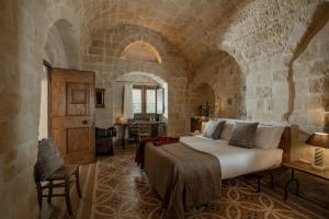 a bedroom with a large bed in a stone room at Locanda Di San Martino Hotel & Thermae Romanae in Matera
