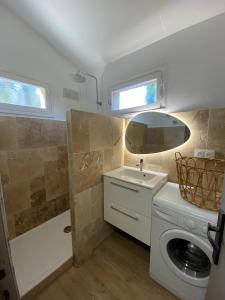 une salle de bain avec une machine à laver et un lavabo dans l'établissement Casa Vista Bella - Maison en Corse avec grande terrasse et accès direct à la mer, Marine de Sant'Ambroggio entre Calvi et L'Ile Rousse, à Lumio