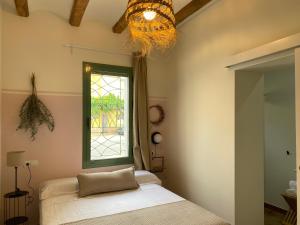 1 dormitorio con cama, ventana y lámpara de araña en Les Filles (antiga Fonda de la Parra) en Deltebre
