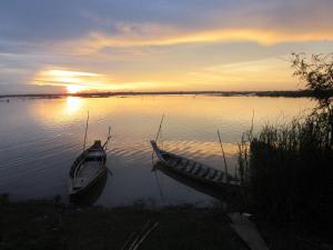 zwei Boote sitzen bei Sonnenuntergang im Wasser in der Unterkunft OBT - The Banana Bungalow 
