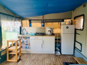 eine kleine Küche mit einem Kühlschrank und einem Tisch in der Unterkunft Luxoriöser Wohnwagen 400 Meter vom Meer in Grömitz. in Lenste