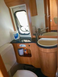 ein kleines Bad mit einem Waschbecken und einem WC in der Unterkunft Luxoriöser Wohnwagen 400 Meter vom Meer in Grömitz. in Lenste