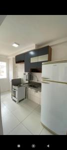 Apartamento Aconchego condomínio florida في فييرا دي سانتانا: مطبخ ابيض فيه ثلاجة بيضاء