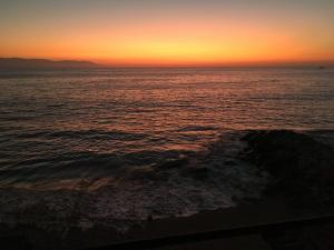 a sunset over the ocean with a rock in the water at Los Tules Ocean Front Suite 902 - 3rd floor in Puerto Vallarta