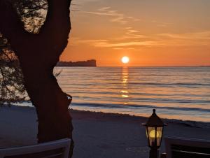 a sunset on the beach with a street light at Dolphin Apt & Studios -Near the Beach in Roda
