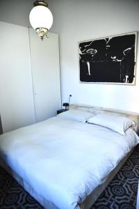 a white bed with a black and white picture on the wall at Cesare Magli & Figli Residenza D'Epoca Luxury Rooms in Molinella