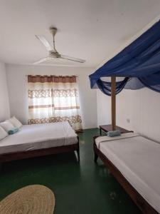 um quarto com 2 camas e uma ventoinha de tecto em Flamingo Guest House ZNZ em Stone Town