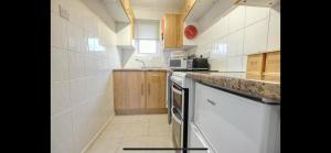 a small kitchen with white appliances and wooden cabinets at Kingfisher Holiday Park 1 Waveney Valley Great Yarmouth in Gorleston-on-Sea