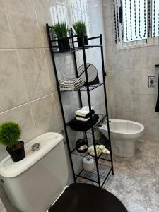 La salle de bains est pourvue de toilettes et d'une étagère avec des plantes. dans l'établissement Apartamento Veracruz 200 m de la Playa, à Gandía