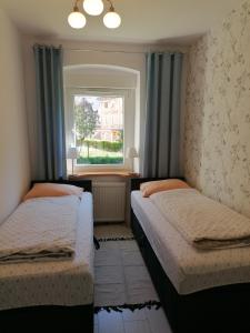 two beds in a room with a window at Apartament u Przewodnika Sudeckiego in Duszniki Zdrój