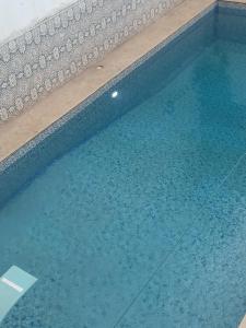 a swimming pool with blue water in a building at Le petit VIP in 'Aïn el Turk