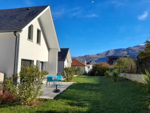 a house with a yard with blue chairs and mountains in the background at Gîte les lys Fleurs des Pyrénées in Argelès-Gazost
