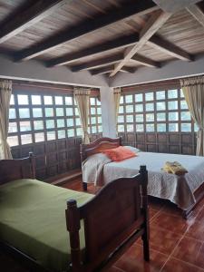 two beds in a room with windows at Chez Alicia Hostal in Villa de Leyva
