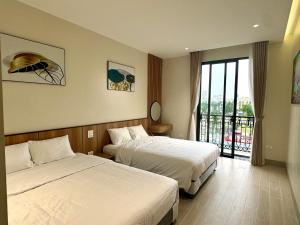 um quarto de hotel com duas camas e uma varanda em MARIS HOTEL SẦM SƠN em Sam Son