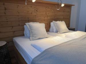 Duas camas com lençóis brancos e almofadas num quarto em Heimat - Das Natur Resort em Prägraten