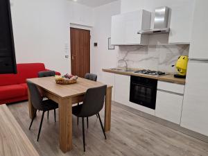eine Küche mit Tisch und Stühlen und einem roten Sofa in der Unterkunft Luppolo Amaro in Sommatino