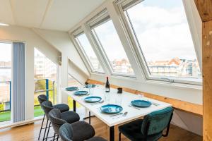 comedor con mesa, sillas y ventanas en Zon Modern beach house, en Bergen aan Zee