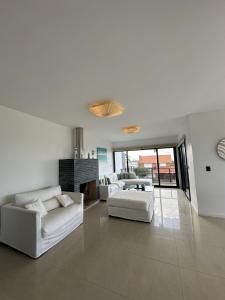 a living room with two white couches and a fireplace at Amplio duplex al mar en manantiales in Punta del Este