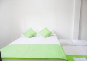 - un lit blanc avec 2 oreillers verts dans l'établissement #2 Suit familiar a solo 1km de la hacienda Nápoles, à Doradal