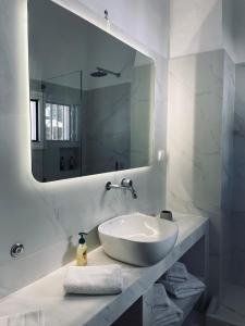 Baño blanco con lavabo y espejo en AVALON Luxury Suites, en Ermoupoli