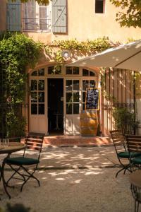 an entrance to a building with two chairs and a table at Hôtel Le Mas des Grès & Restaurant Sous les Platanes in Lagnes