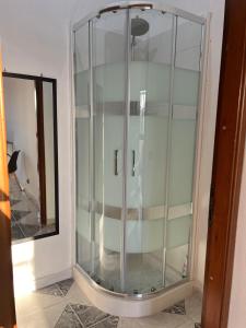 Baño con ducha de cristal junto a un espejo en Villa Maria, en Tre Fontane