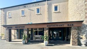 un bar ristorante di fronte a un edificio in mattoni di The Hedges Hotel a Stranocum