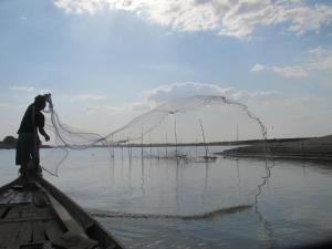 um homem num barco com uma rede na água em OBT - The Mango Bungalow 