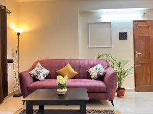 a purple couch in a living room with a table at Central 2BHK Premium Apartment in Hyderabad