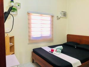 ein Schlafzimmer mit einem Bett mit einer schwarzen Decke und einem Fenster in der Unterkunft Wakim’s INN in Coron