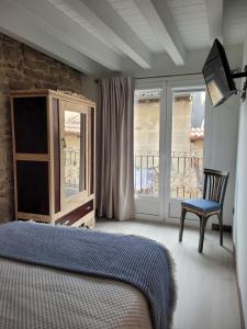 1 dormitorio con 1 cama, 1 silla y ventanas en Casa Rural Garabitero, en Laguardia