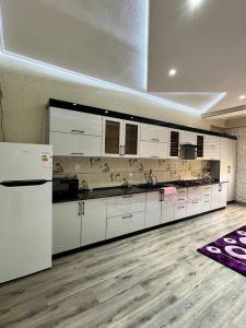 a large kitchen with white cabinets and a wooden floor at Bonushka 5 in Uzbankinty