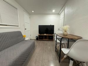 a living room with a bed and a table with a television at Guest House in West Covina