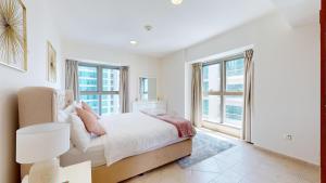a bedroom with a bed and large windows at Elite Estates - Both Sea & Marina View Princess Tower Unit in Dubai