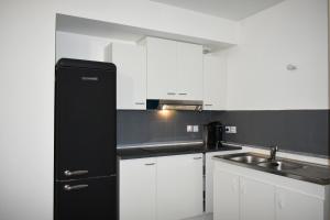 a kitchen with a black refrigerator and a sink at Appartement Parisien - Jeux Olympiques 2024 in Charenton-le-Pont