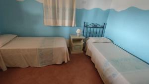 2 camas en una habitación con paredes azules en Villa Pidda a San Teodoro, en San Teodoro