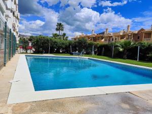 une grande piscine bleue en face d'un bâtiment dans l'établissement La Marina Beach 3 bedrooms Sun & Golf, à Torre de Benagalbón